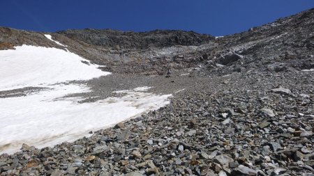 Ascension de l’éboulis on aperçoit la corniche du col de la Pyramide