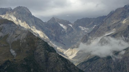 Vue en direction du vallon du Sélé avec la barre de l’Ouro dans une tâche de soleil.