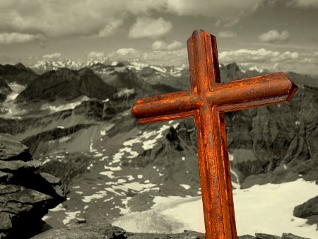 La croix sommitale et le lointain massif du Mont Blanc en arrière-plan.